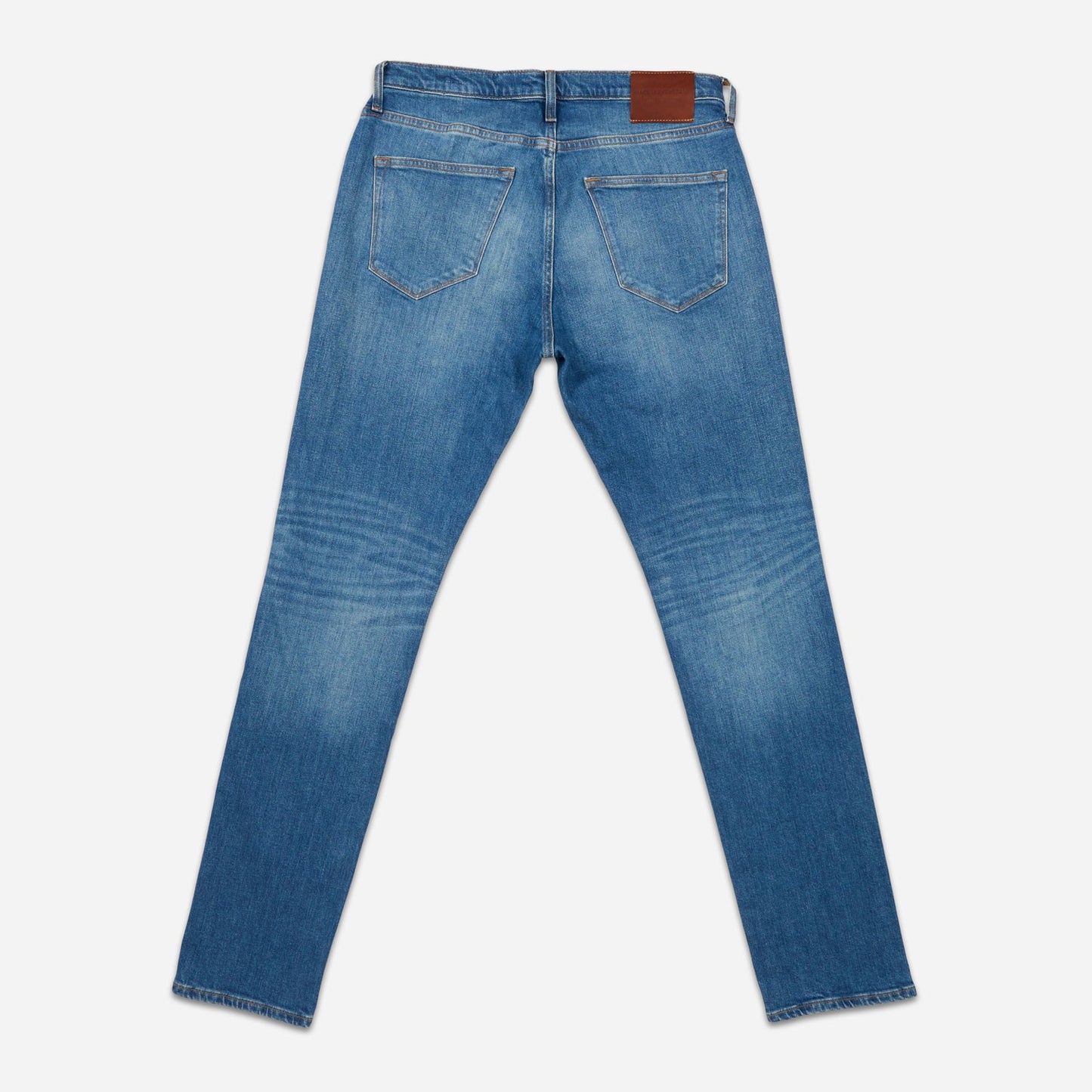 back of folded pair of men's athletic taper medium light blue jeans with slight wear