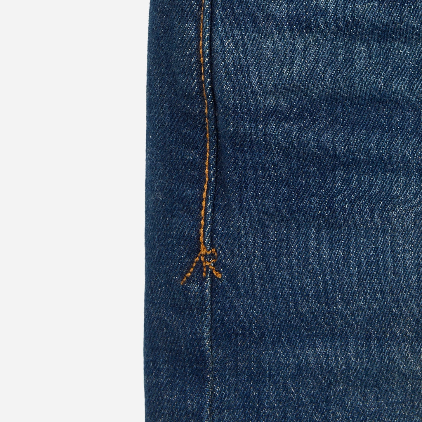 close up of stitching on pair of men's athletic taper blue jeans with slight wear 