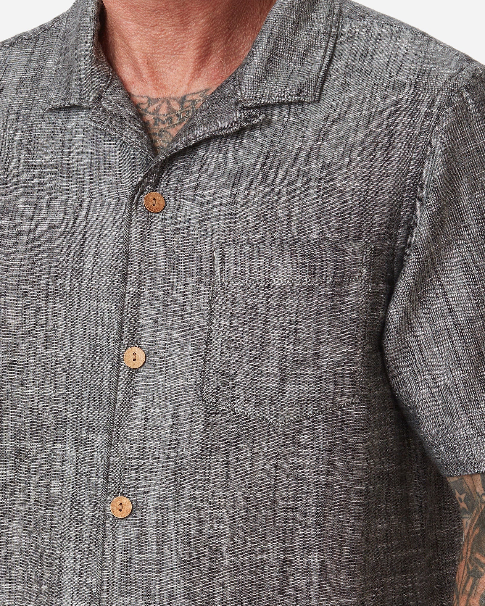 Zoomed-in neck, left-breast pocket, buttons, and collar on model wearing Ace Rivington "Black" Double gauze soft-textured cotton fabric camp collar shirt with coconut buttons and left-breast pocket 