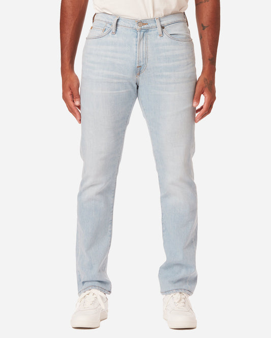 model facing directly forward wearing Ace Rivington super light blue denim jeans with antique nickel detailing with a pair of white Diadora B Elite sneaker shoes and tucked white Ace Rivington super soft supima short-sleeved tee shirt
