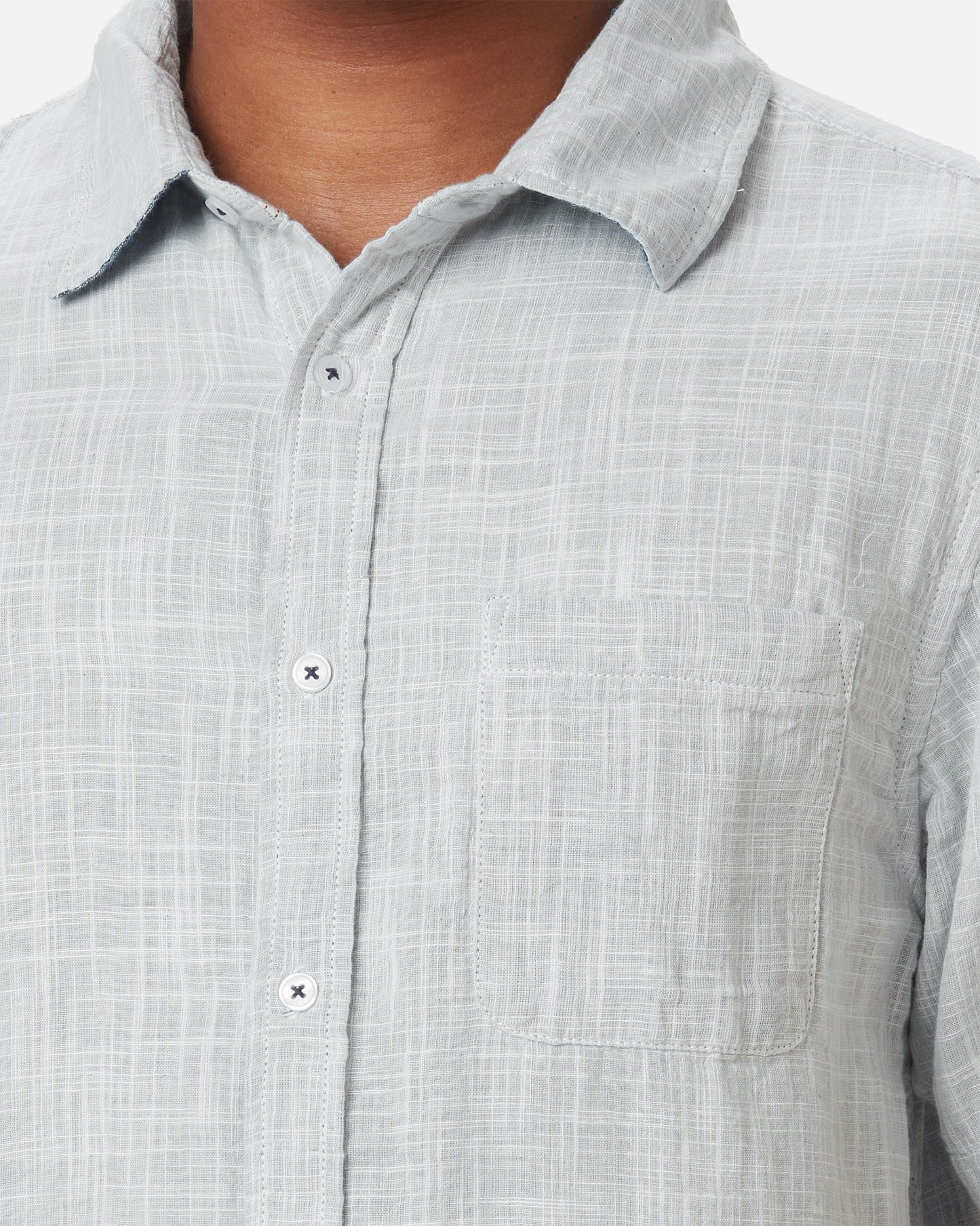 Zoom in of neck, collar, breast pocket, and buttons on model wearing Ace Rivington collared grey short-sleeved double gauze soft-textured cotton shirt with indigo blue interior, pearl buttons, and left-breast pocket 
